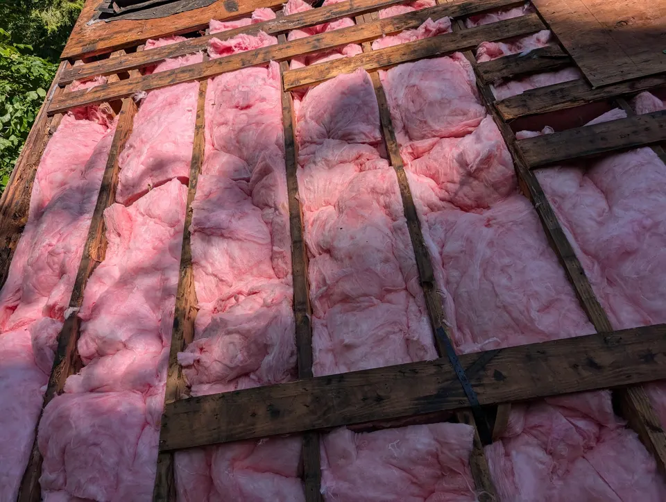 Exposed roof rafters with insulation during a rot repair job