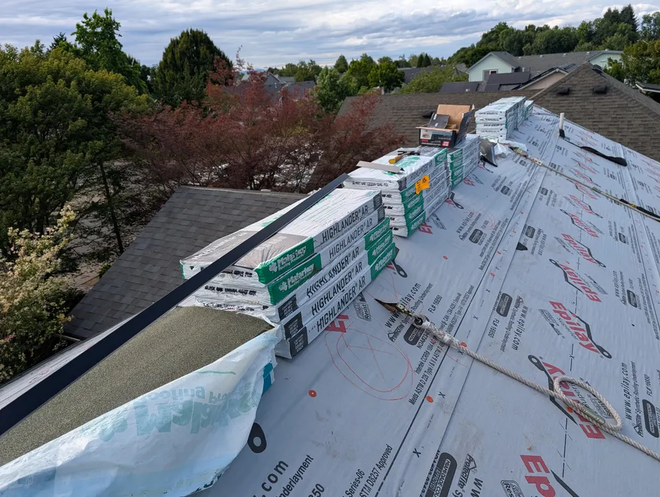 Pitched roof with underlayment rolled out and shingle stacks ready