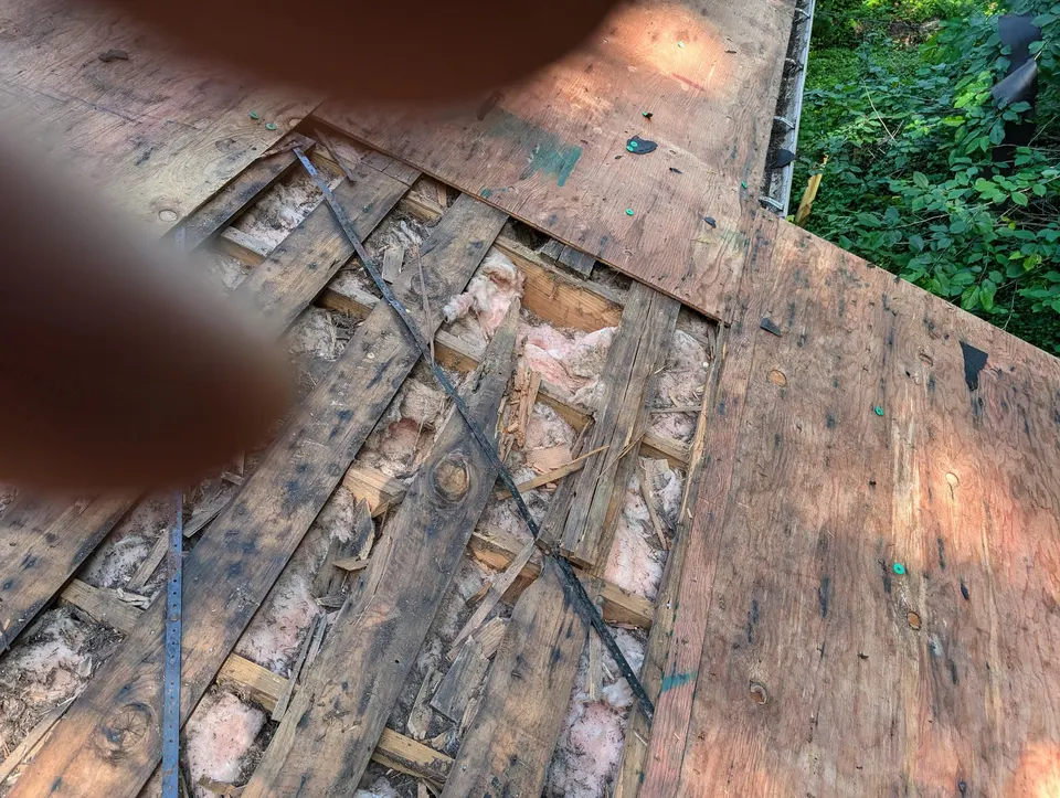 Stripped roof deck with rot damage and new plywood sheathing during a rot repair